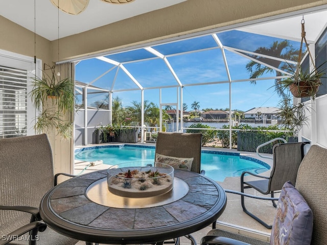 view of pool featuring a patio, glass enclosure, and a water view