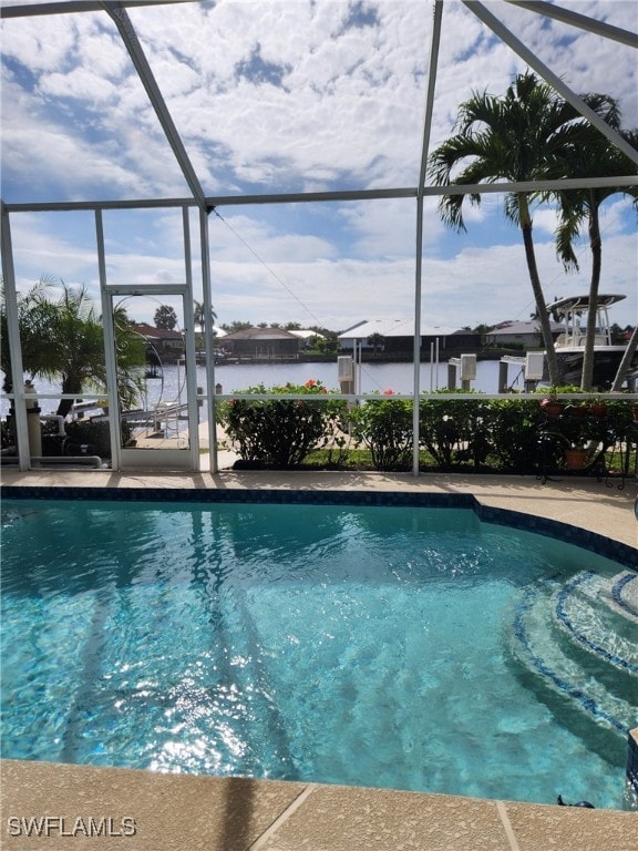 view of pool featuring glass enclosure and a water view