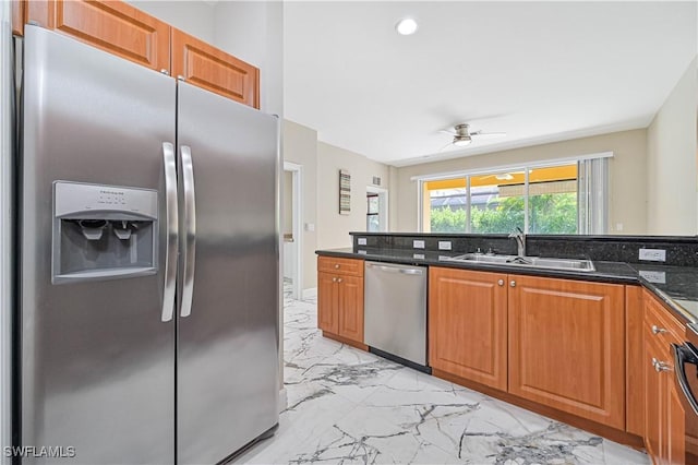 kitchen featuring stainless steel appliances, sink, dark stone countertops, and ceiling fan