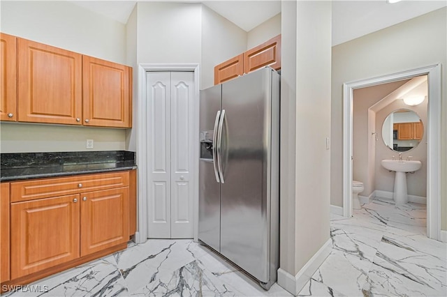 kitchen with stainless steel fridge and dark stone counters