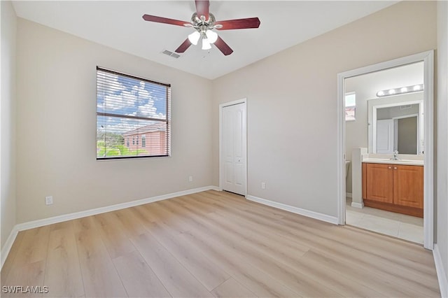 unfurnished bedroom with connected bathroom, sink, light hardwood / wood-style flooring, a closet, and ceiling fan