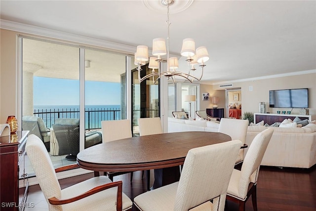 dining room with ornamental molding, a water view, dark wood-type flooring, and a notable chandelier