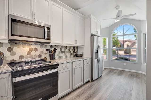 kitchen with vaulted ceiling, white cabinetry, backsplash, light stone counters, and stainless steel appliances