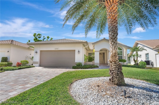 mediterranean / spanish home with a garage, a front lawn, and central air condition unit