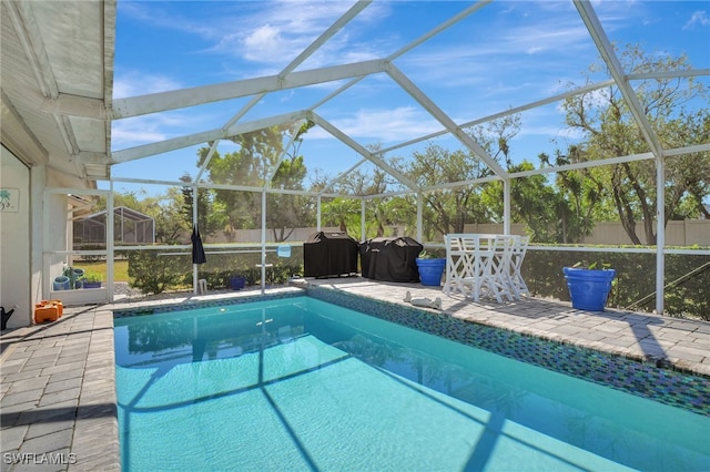 view of swimming pool featuring area for grilling, a patio, and glass enclosure