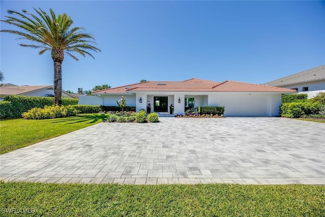 4611 Crayton Rd, Naples, FL 34103 - mediterranean / spanish-style house featuring decorative driveway, a tiled roof, a garage, a front lawn, and stucco siding