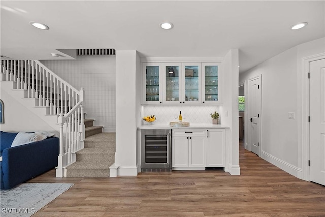 4611 Crayton Rd, Naples, FL 34103 - indoor bar with wine cooler, stairs, light wood-style flooring, recessed lighting, and decorative backsplash