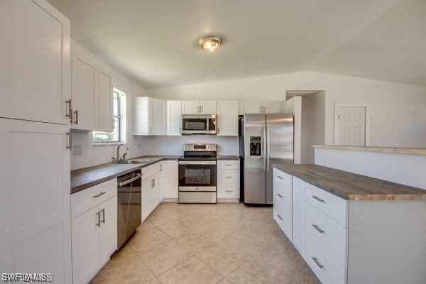 kitchen with white cabinetry, sink, vaulted ceiling, and stainless steel appliances