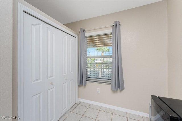 bedroom with a closet, baseboards, and light tile patterned floors