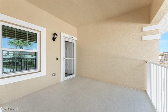 property entrance featuring a balcony and stucco siding