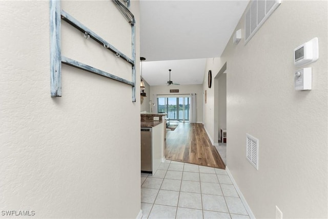 hallway with tile patterned flooring, visible vents, and baseboards