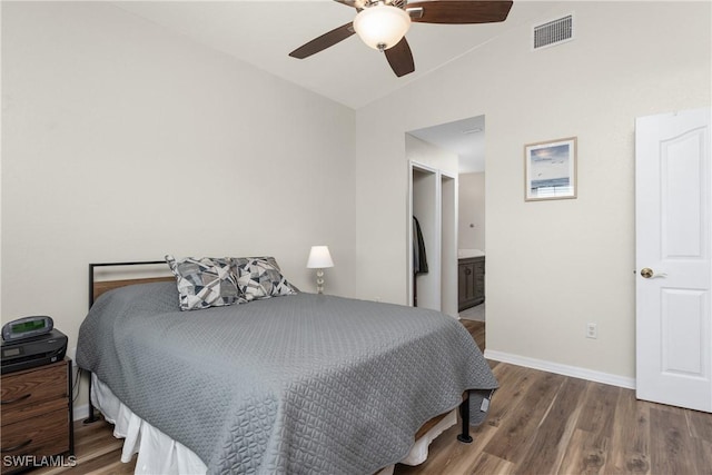 bedroom featuring vaulted ceiling, wood finished floors, visible vents, and baseboards