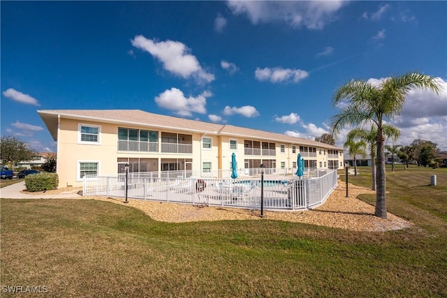 exterior space with a community pool, fence, a lawn, and stucco siding