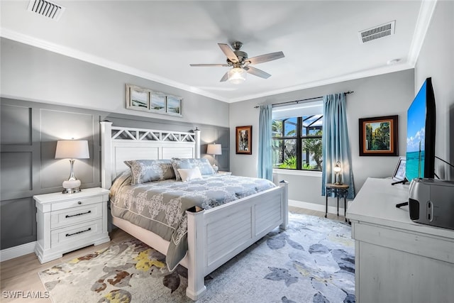 bedroom with ornamental molding, light wood-style flooring, visible vents, and a ceiling fan