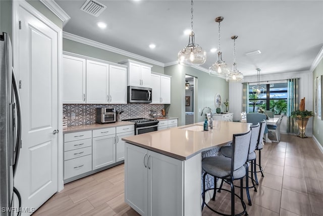 kitchen featuring stainless steel appliances, light countertops, white cabinetry, a sink, and a kitchen island with sink