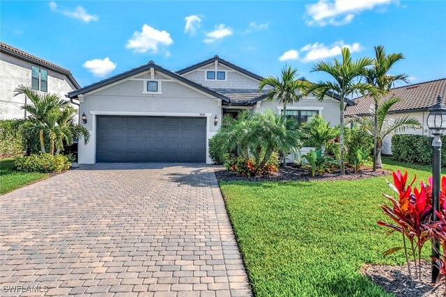 view of front of property featuring a garage, decorative driveway, a front yard, and stucco siding