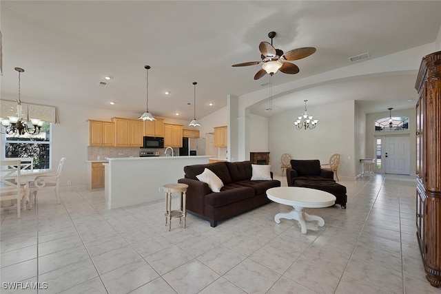 living room featuring lofted ceiling, sink, ceiling fan with notable chandelier, and light tile patterned floors