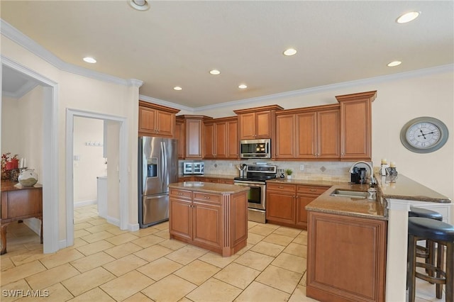 kitchen featuring stainless steel appliances, a peninsula, a sink, brown cabinetry, and a kitchen bar