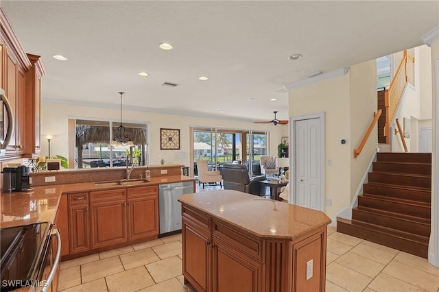 kitchen featuring appliances with stainless steel finishes, brown cabinets, a sink, and light stone counters