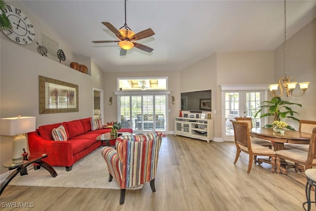 living room featuring ceiling fan with notable chandelier, high vaulted ceiling, and light hardwood / wood-style flooring