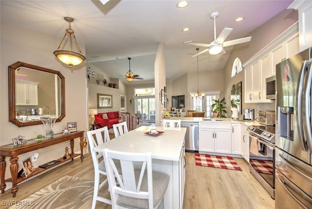 kitchen with white cabinetry, appliances with stainless steel finishes, decorative light fixtures, and kitchen peninsula