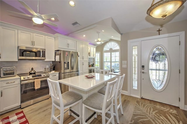 kitchen featuring lofted ceiling, appliances with stainless steel finishes, decorative backsplash, and white cabinets