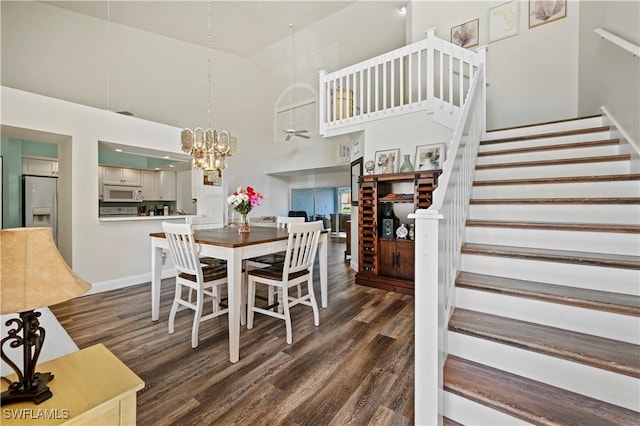 dining area with dark hardwood / wood-style flooring, a high ceiling, and a notable chandelier