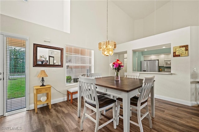 dining space with dark hardwood / wood-style floors, a chandelier, and a towering ceiling