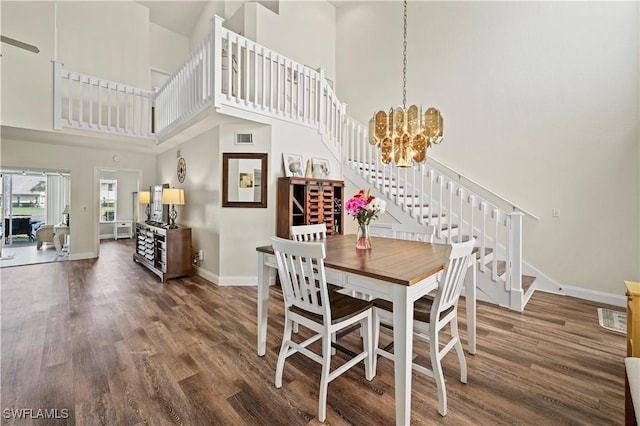 dining area with dark hardwood / wood-style flooring, a towering ceiling, and a chandelier