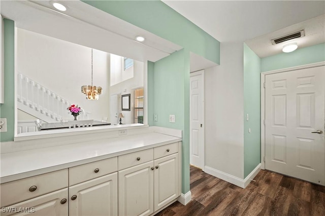 kitchen with dark hardwood / wood-style floors, a notable chandelier, decorative light fixtures, and white cabinets