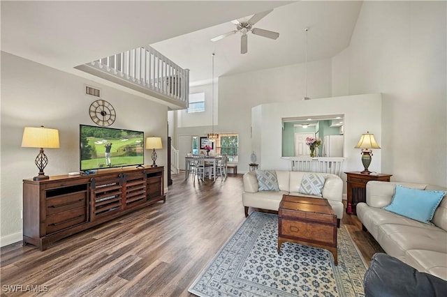 living room featuring hardwood / wood-style flooring, ceiling fan, and a towering ceiling