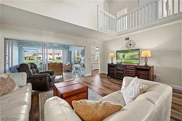 living room with a high ceiling and dark wood-type flooring