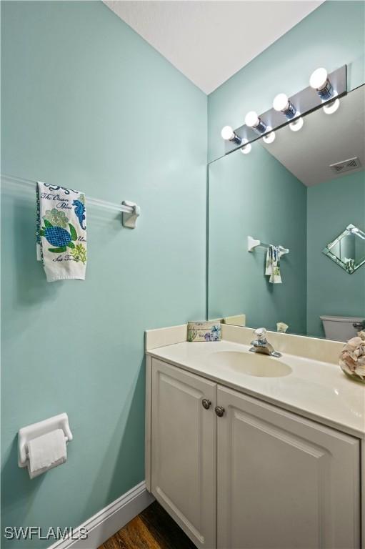 bathroom with vanity, wood-type flooring, and toilet