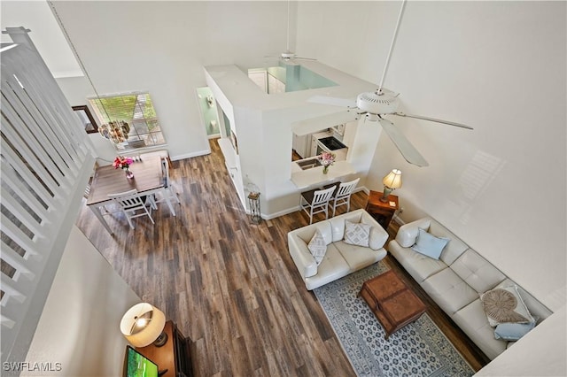 living room with ceiling fan, a towering ceiling, and dark hardwood / wood-style flooring