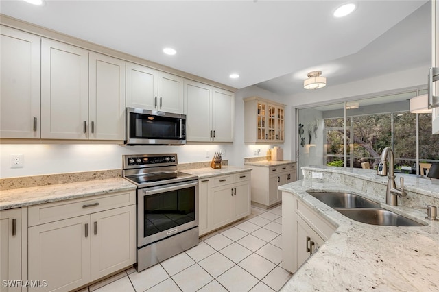 kitchen featuring appliances with stainless steel finishes, sink, and light stone counters