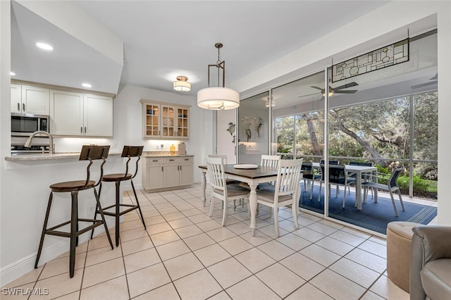 dining area with light tile patterned flooring, sink, and ceiling fan