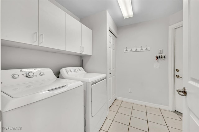 laundry room featuring cabinets, washing machine and dryer, and light tile patterned floors