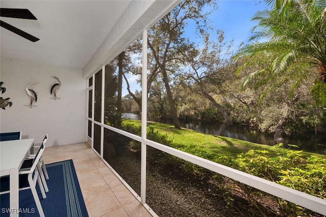 unfurnished sunroom featuring a water view and ceiling fan