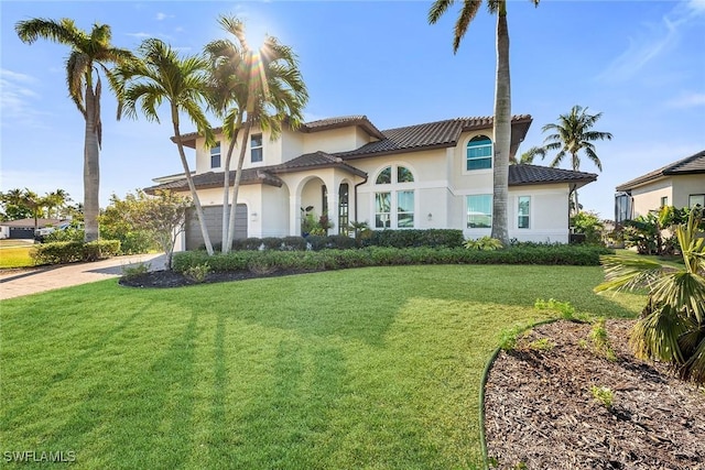 mediterranean / spanish-style house featuring a garage and a front lawn