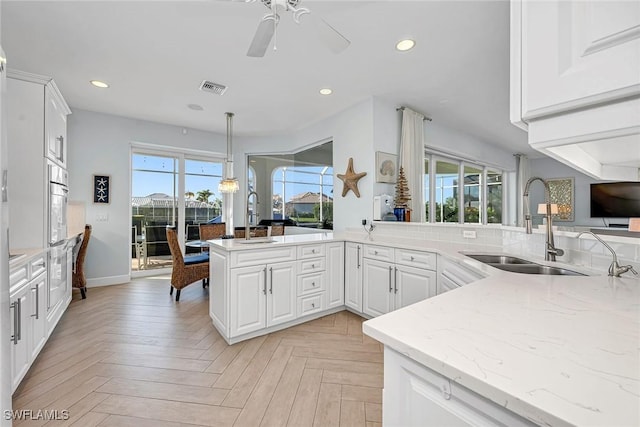 kitchen with white cabinetry, kitchen peninsula, sink, and light parquet floors