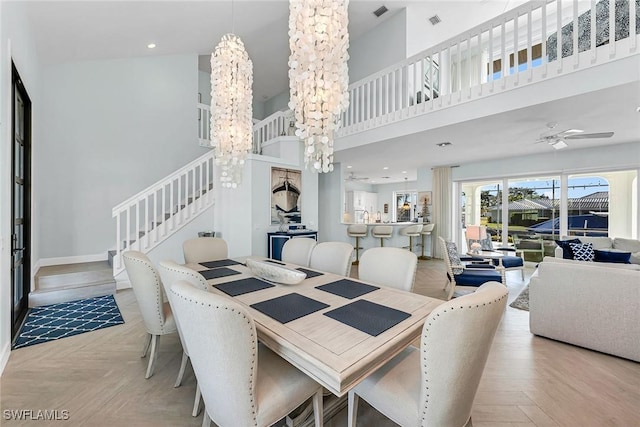 dining area featuring a towering ceiling, ceiling fan with notable chandelier, and light parquet flooring