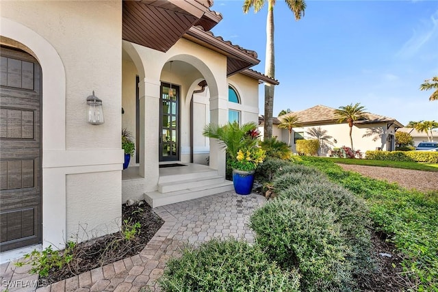 doorway to property featuring a tiled roof and stucco siding