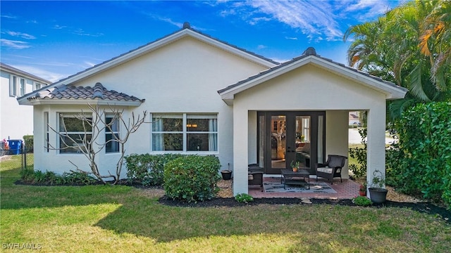 view of front of home featuring french doors, a patio area, and a front lawn