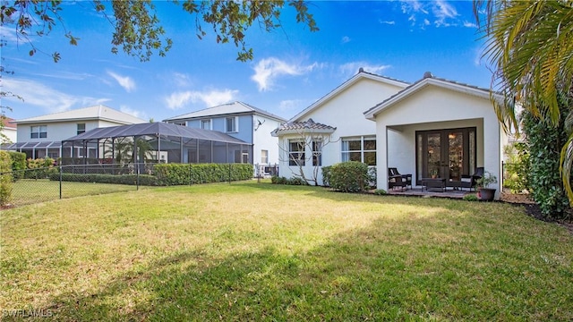 back of house featuring a lanai, a yard, and french doors