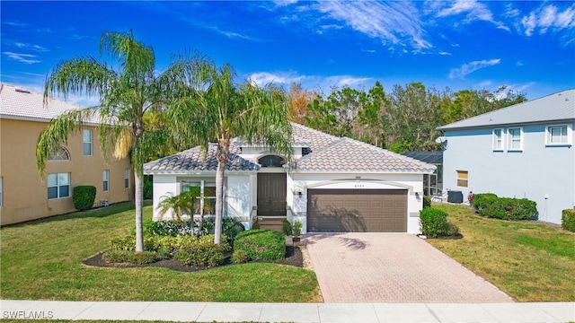 view of front of property featuring a tiled roof, a front lawn, decorative driveway, and an attached garage