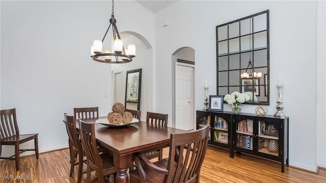 dining area featuring a high ceiling, hardwood / wood-style floors, and a chandelier