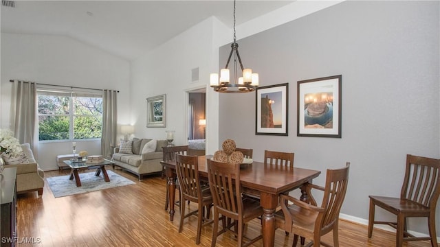 dining room featuring an inviting chandelier, lofted ceiling, and wood-type flooring