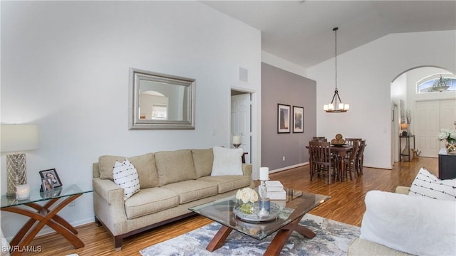 living room with hardwood / wood-style flooring, high vaulted ceiling, and a notable chandelier