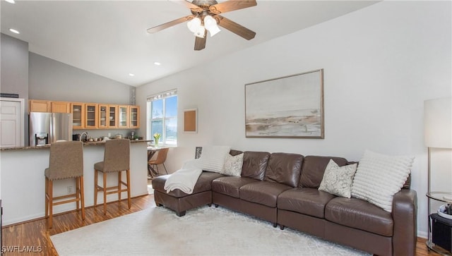 living room featuring ceiling fan, lofted ceiling, sink, and light hardwood / wood-style floors