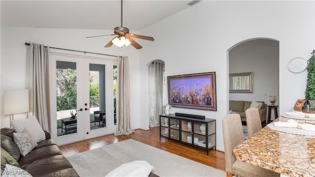 living room featuring lofted ceiling, light hardwood / wood-style floors, french doors, and ceiling fan